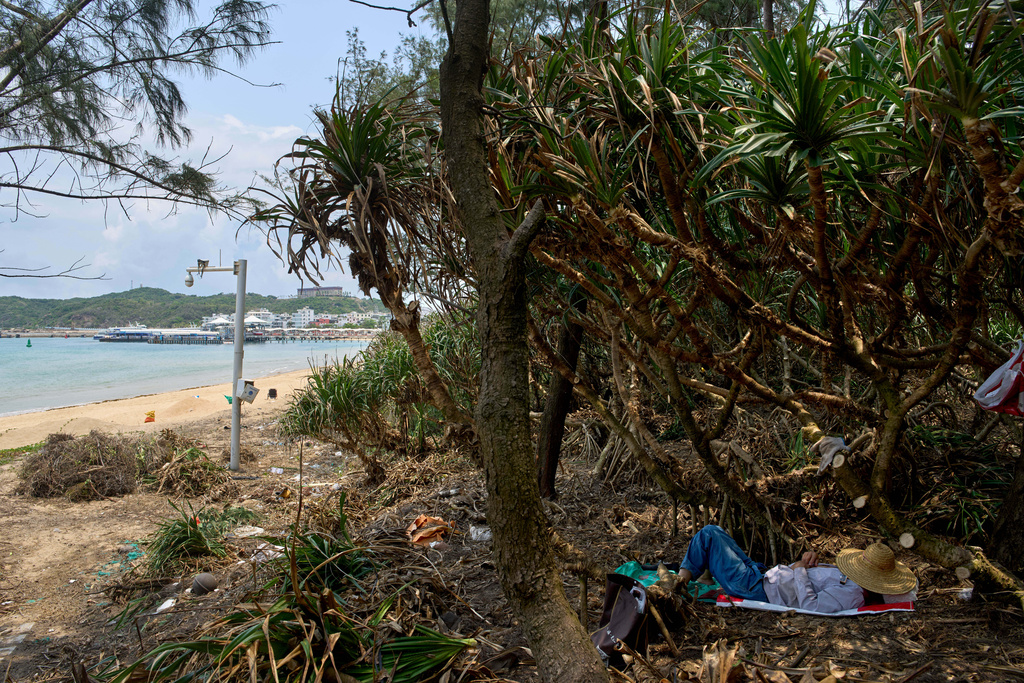 A worker naps near a security camera along a deserted beach near Sanya city in southern China's Hainan province, Saturday, April 26, 2025. (AP Photo/Ng Han Guan)