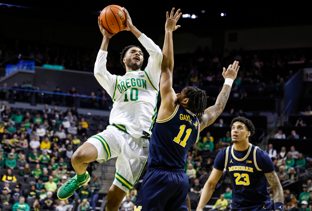 Oregon forward Kwame Evans Jr. (10) shoots against Michigan guard Roddy Gayle Jr. (11) as forward Yaxel Lendeborg (23) looks on in the first half of an NCAA college basketball game in Eugene, Ore., Saturday, Jan. 17, 2026. (AP Photo/Thomas Boyd)