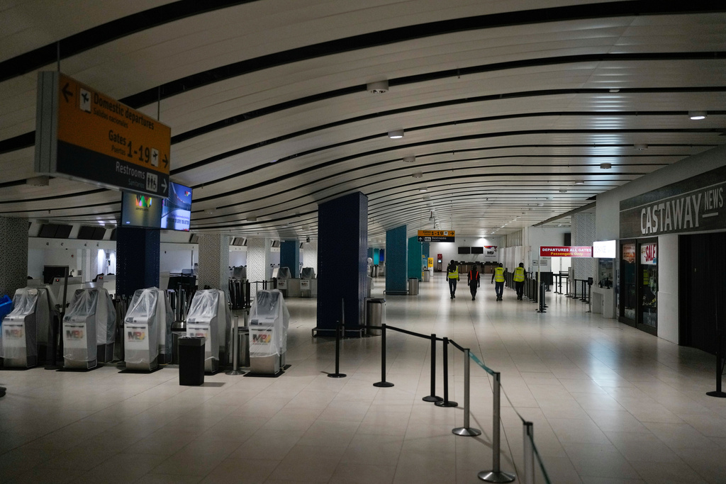 Workers walk through Sangster International Airport, which was closed after Hurricane Melissa, in Montego Bay, Jamaica, Friday, Oct. 31, 2025. (AP Photo/Matias Delacroix)