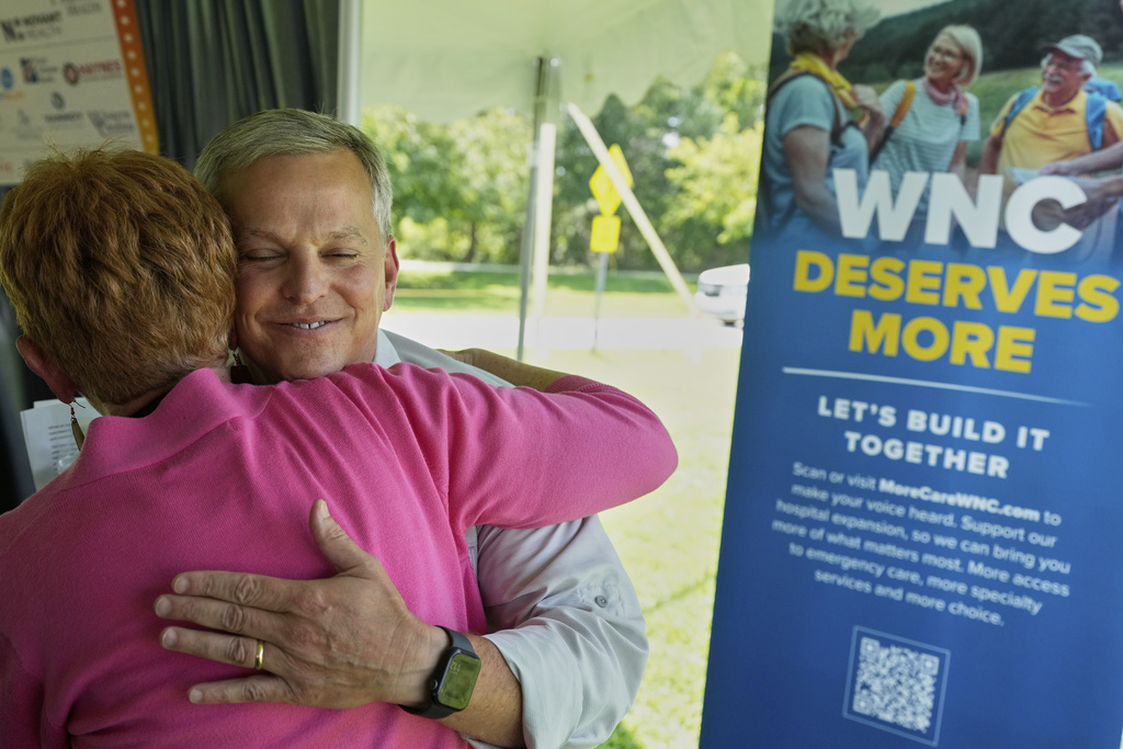 North Carolina Gov. Josh Stein hugs Brevard Mayor, Maureen Copelof at the Land of Sky Regional Council's event, Aug. 20, 2025, Fletcher, N.C. (AP Photo/Chris Carlson)