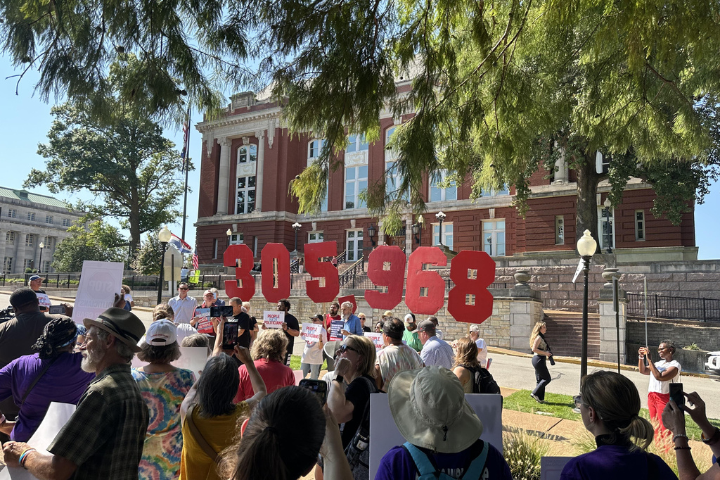 In this photo taken with a smartphone, people opposing a congressional redistricting plan rally outside the Missouri Supreme Court in Jefferson City, Mo., Wednesday, Sept. 2, 2026, while displaying the number of petition signatures submitted seeking a statewide vote on the measure. (AP Photo/David A. Lieb)