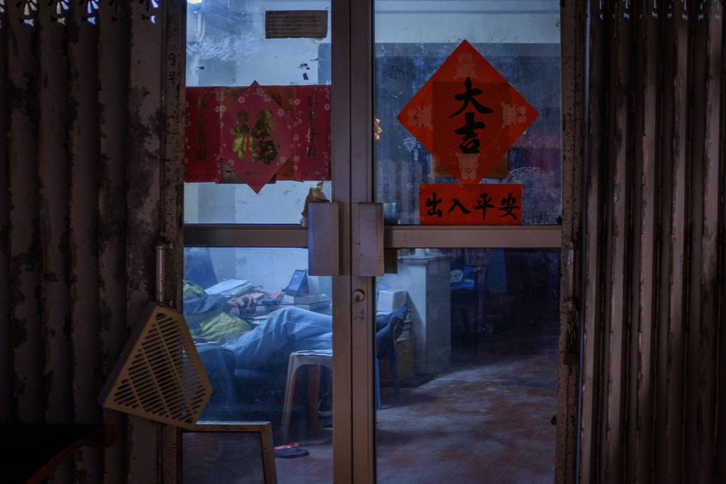 A man watches his tablet inside his home decorated with couplets on the first day of the Lunar New Year in Hong Kong, Feb. 17, 2026. (AP Photo/May James)