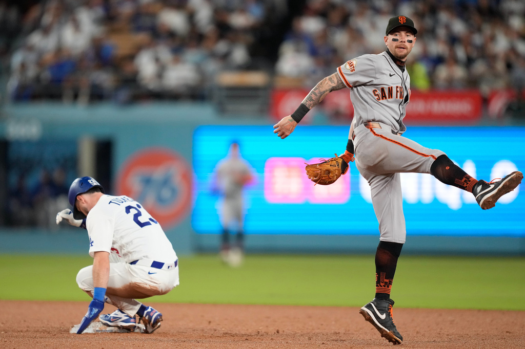 San Francisco Giants shortstop Christian Koss, right, throws out Los Angeles Dodgers' Teoscar Hernández at first after Kyle Tucker, left, was forced out at second during the fourth inning of a baseball game Friday, Sept. 18, 2026, in Los Angeles. (AP Photo/Mark J. Terrill)