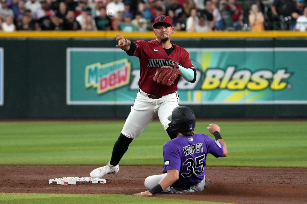 Arizona Diamondbacks shortstop Ildemaro Vargas turns the double play while avoiding Colorado Rockies' Connor Norby (35) on a ball hit by Jake McCarthy in the third inning of a baseball game, Tuesday, Aug 11, 2026, in Phoenix. (AP Photo/Rick Scuteri)