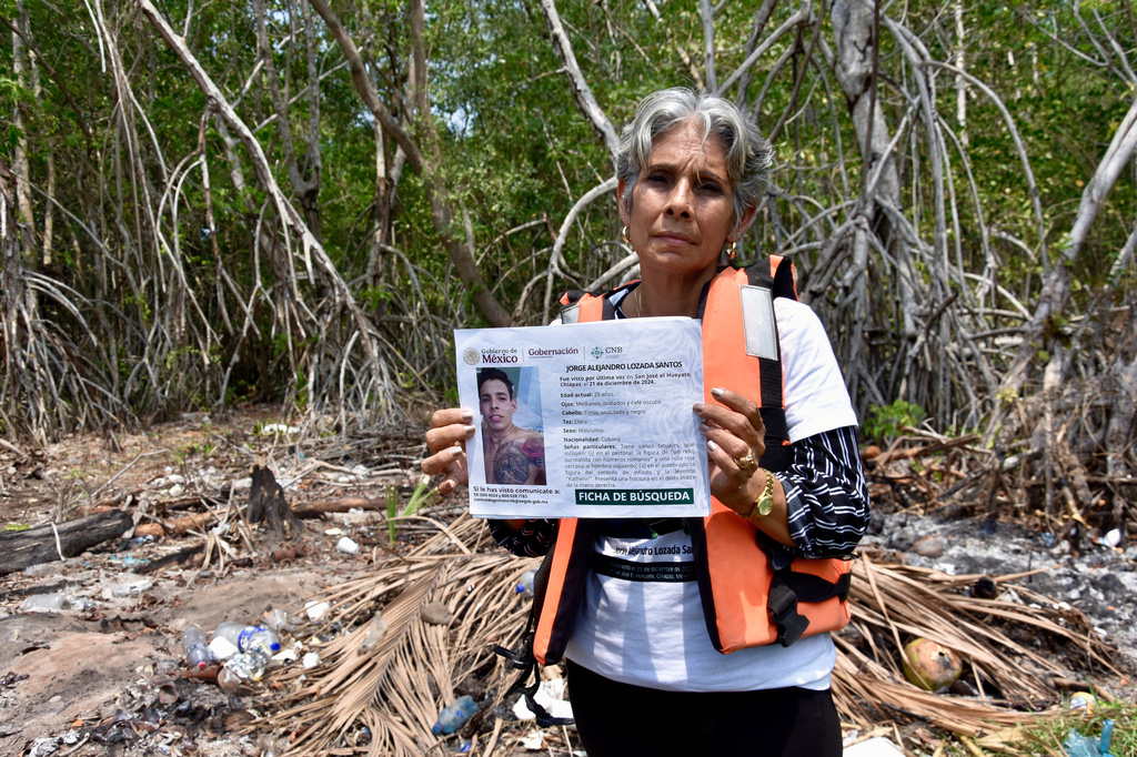 Alicia Santos Torres, from Cuba, shows a sign of her missing son Jorge Alejandro Lozada in San Jose Hueyate, Chiapas state, Mexico, Saturday, May 9, 2026, during a search for migrants who vanished in late 2024 along a maritime smuggling route to the U.S. (AP Photo/Edgar H. Clemente)