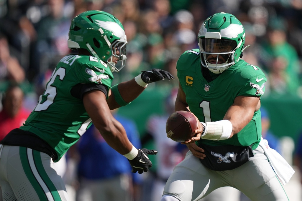 Philadelphia Eagles quarterback Jalen Hurts, right, hands off to Eagles running back Saquon Barkley (26) who runs for a touchdown during the first half of an NFL football game against the New York Giants on Sunday, Oct. 26, 2025, in Philadelphia. (AP Photo/Matt Slocum)