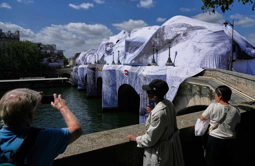 People take pictures of "The Pont Neuf Cave," an inflated art installation by French street artist JR, on Paris' oldest bridge, the Pont Neuf, Thursday, May 21, 2026, which will be open to the public from June 6-28. (AP Photo/Michel Euler)