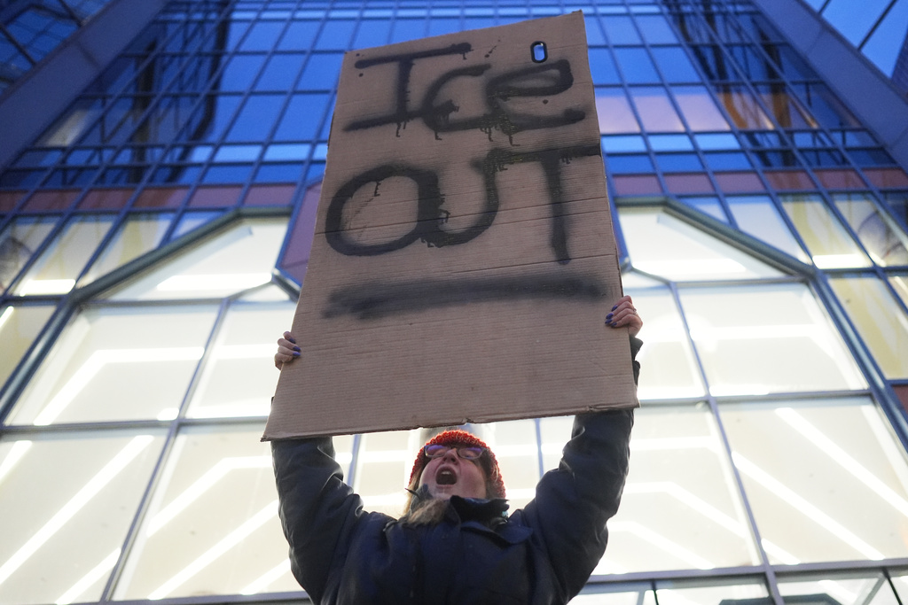 A demonstrator holds a sign reading "ICE OUT" during a protest outside the office of Sen. Amy Klobuchar, D-Minn., on Monday, Jan. 26, 2026, in Minneapolis. (AP Photo/Adam Gray)