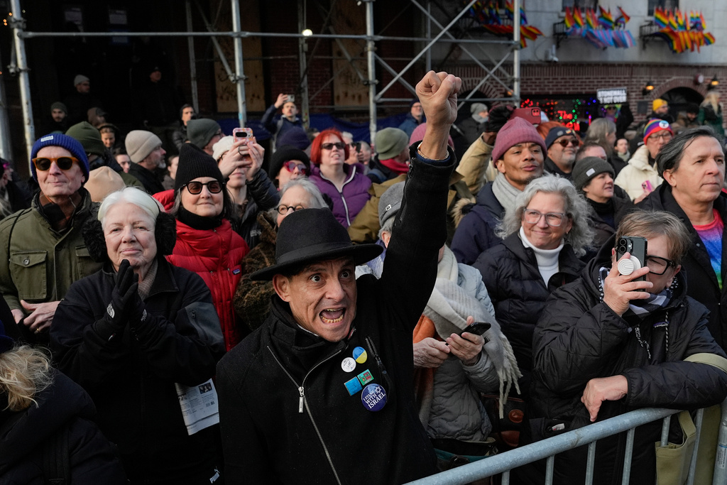 People react outside the Stonewall Inn as New York politicians and activists raise a rainbow flag on a pole in Christopher Park across the street, Thursday, Feb. 12, 2026, in New York, a few days after it was removed by the National Park Service to comply with guidance from the Trump administration. (AP Photo/Yuki Iwamura)