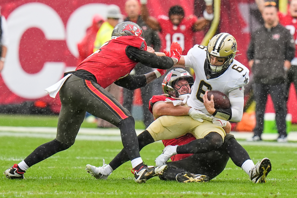 New Orleans Saints quarterback Tyler Shough (6) is sacked by Tampa Bay Buccaneers defensive tackle Greg Gaines and linebacker Haason Reddick, left, in the first half of an NFL football game, Sunday, Dec. 7, 2025, in Tampa, Fla. (AP Photo/Chris O'Meara)