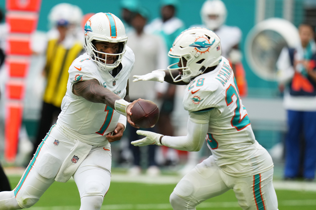 Miami Dolphins quarterback Tua Tagovailoa (1) hands the football to running back De'Von Achane (28) during the second half of an NFL football game against the New Orleans Saints Sunday, Nov. 30, 2025, in Miami Gardens, Fla. (AP Photo/Lynne Sladky)