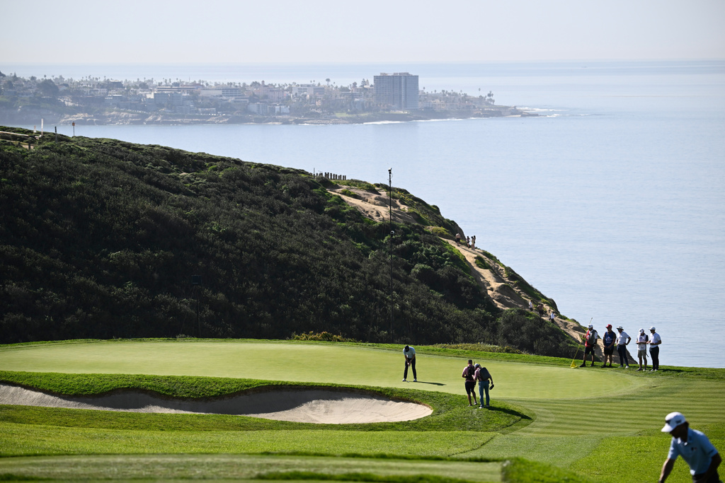 Justin Rose, of England, at right, putts on the third green of the South Course at Torrey Pines during the third round of the Farmers Insurance Open golf tournament Saturday, Jan. 31, 2026, in San Diego. (AP Photo/Denis Poroy)