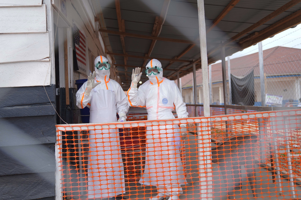Health workers in protective gear wave inside an Ebola treatment centre in Bunia, Congo, Monday, Aug. 10, 2026. (AP Photo/Dieudonne Dirole)