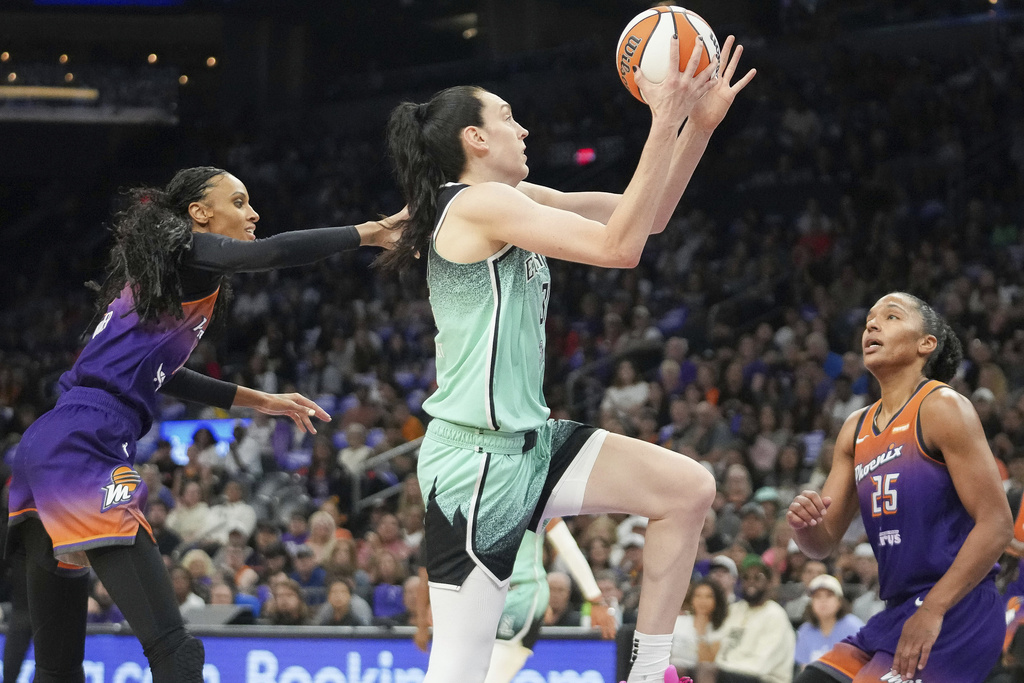 New York Liberty forward Breanna Stewart, center, drives to the basket between Phoenix Mercury forward DeWanna Bonner, left, and Alyssa Thomas, right, during the first half of Game 1 in the first round of the WNBA basketball playoffs Sunday, Sept. 14, 2025, in Phoenix. (AP Photo/Darryl Webb)