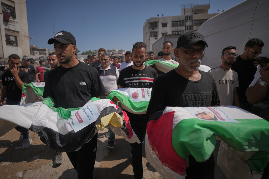 Mourners carry the flag-draped bodies of Palestinians killed in Israeli strikes during the war with Hamas, whose remains were recently recovered from the rubble, in Gaza City, Thursday, Aug. 20, 2026. (AP Photo/Jehad Alshrafi)