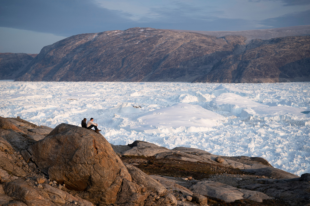 FILE - NYU student researchers sit on top of a rock overlooking the Helheim glacier in Greenland, Aug. 16, 2019. (AP Photo/Felipe Dana, File)