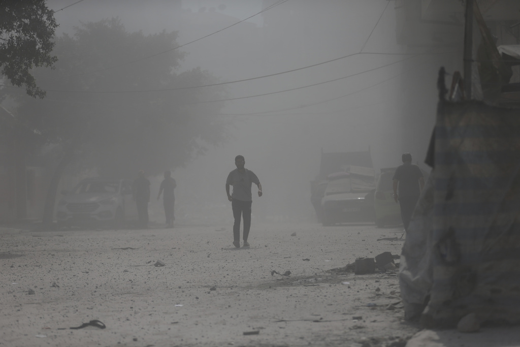 Palestinians walk through dust moments after an Israeli military strike that destroyed a building in Gaza City, Monday, Sept. 15, 2025. (AP Photo/Yousef Al Zanoun)