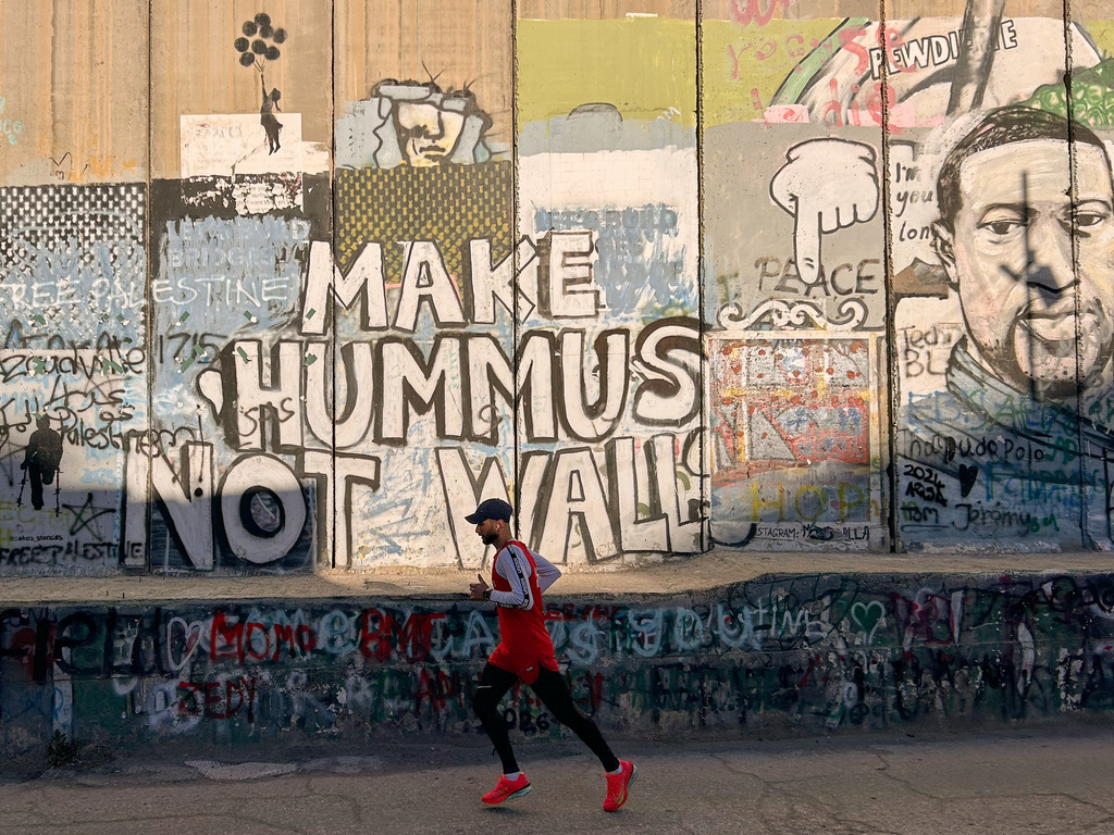 Palestinian Mohamad Al-Assi, who was released from Israeli detention six months ago, runs past Israel's separation wall as he trains ahead of the Palestine Marathon in the West Bank city of Bethlehem, Thursday, May 7, 2026. (AP Photo/Sam Metz)
