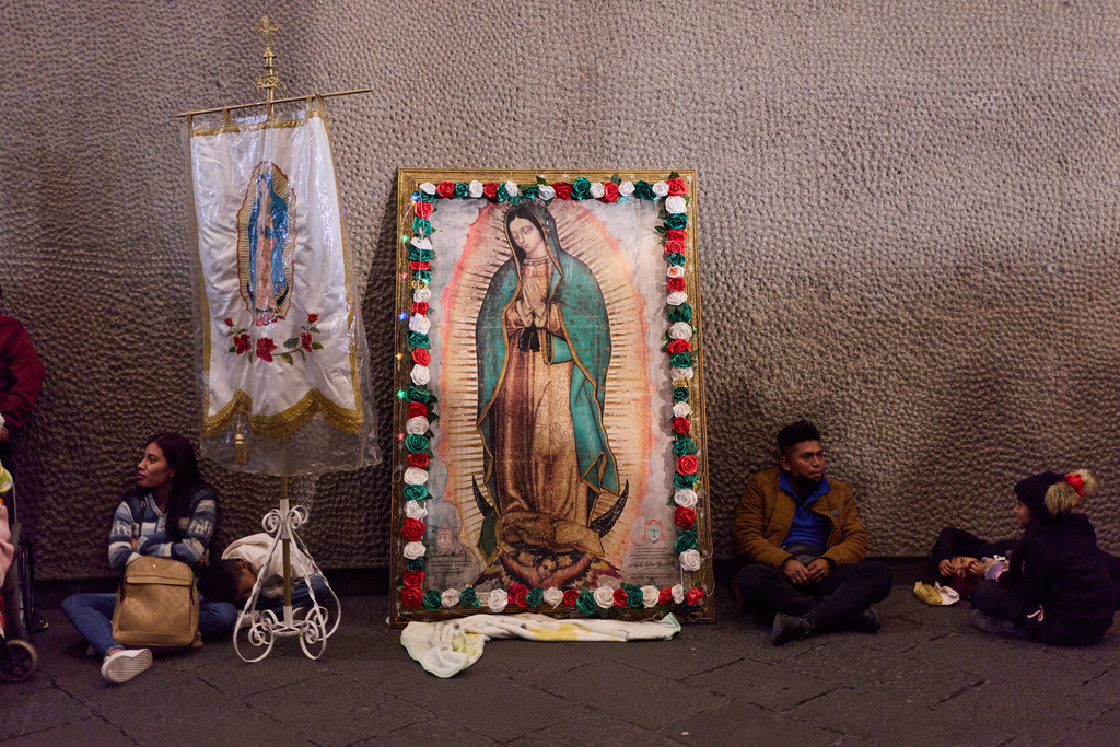 Pilgrims rest next to framed image of the Virgin of Guadalupe outside the Basilica of Guadalupe, in Mexico City, Thursday, Dec. 11, 2025, the day before her feast day. (AP Photo/Claudia Rosel)