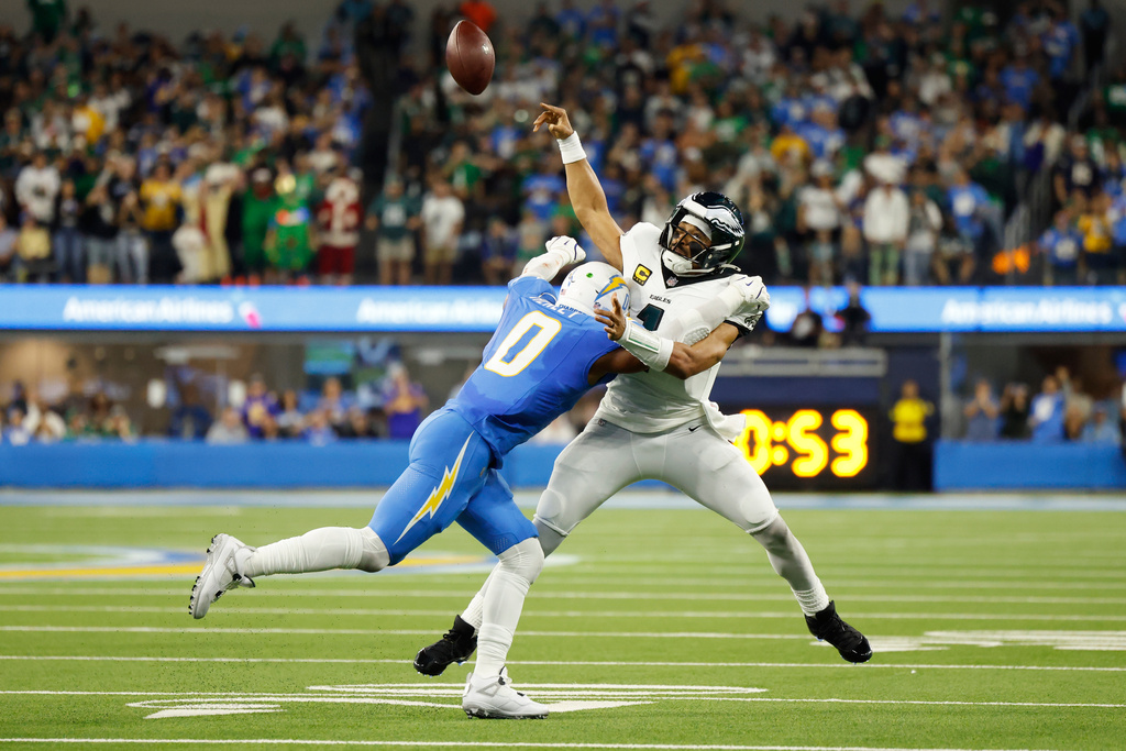 Philadelphia Eagles quarterback Jalen Hurts (1) throws as he is tackled by Los Angeles Chargers linebacker Daiyan Henley (0) during the first half of an NFL football game Monday, Dec. 8, 2025, in Inglewood, Calif. (AP Photo/Caroline Brehman)