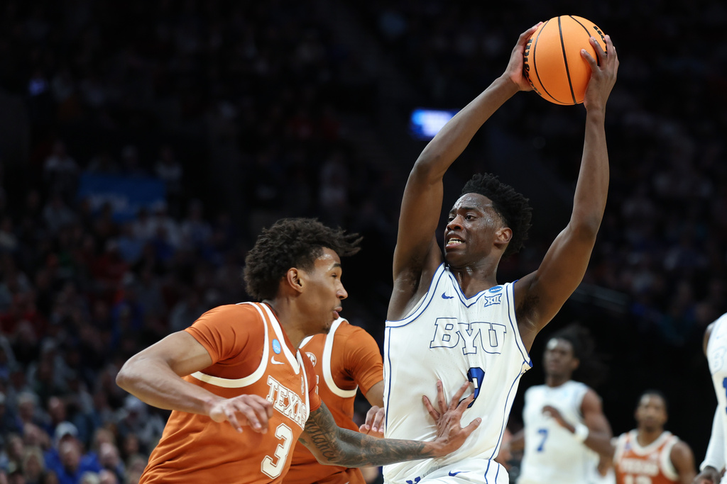 BYU forward AJ Dybantsa, right, goes to the basket past Texas forward Dailyn Swain (3) during the first half in the first round of the NCAA college basketball tournament Thursday, March 19, 2026, in Portland, Ore. (AP Photo/Craig Mitchelldyer)