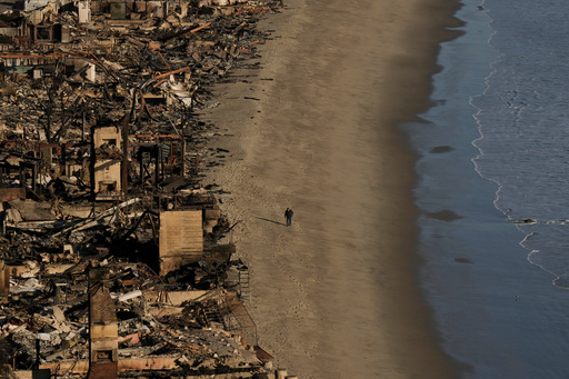 FILE - A person walks on the beach next to homes damaged by the Palisades Fire on Jan. 16, 2025, in Malibu, Calif. (AP Photo/Jae C. Hong, File) FILE - A person walks on the beach next to homes damaged by the Palisades Fire on Jan. 16, 2025, in Malibu, Calif. (AP Photo/Jae C. Hong, File)