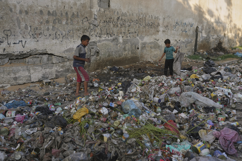 Palestinian children sort through trash as they look for plastic to use in making fire for cooking, in Gaza City, Wednesday, Aug. 27, 2025. (AP Photo/Jehad Alshrafi)