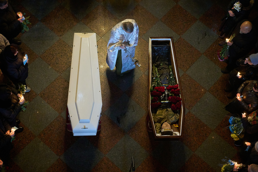 A priest conducts a service as people say the last goodbye to Ukrainian soldiers Myroslava Kopcha and Artur Vilchynski, who were killed in Russia-Ukraine war, during a funeral ceremony at St. Michael Cathedral in Kyiv, Ukraine, Friday, Nov. 28, 2025. (AP Photo/Efrem Lukatsky)