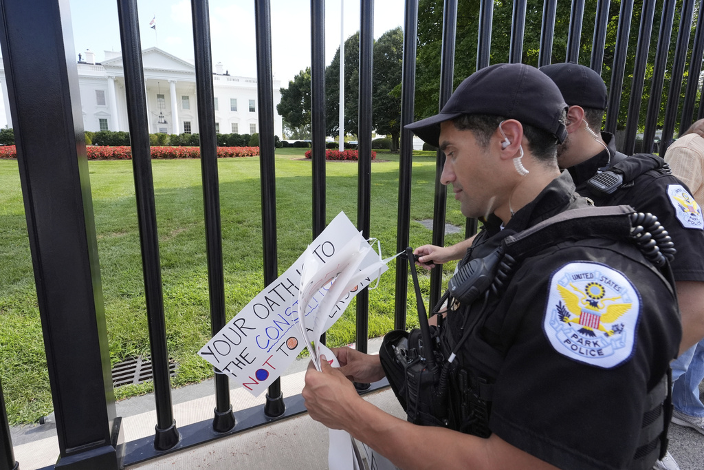 Officers with the Park Police remove signs near the White House as activists protest President Donald Trump's federal takeover of policing of the District of Columbia, Saturday, Aug. 16, 2025, in Washington. (AP Photo/Alex Brandon)