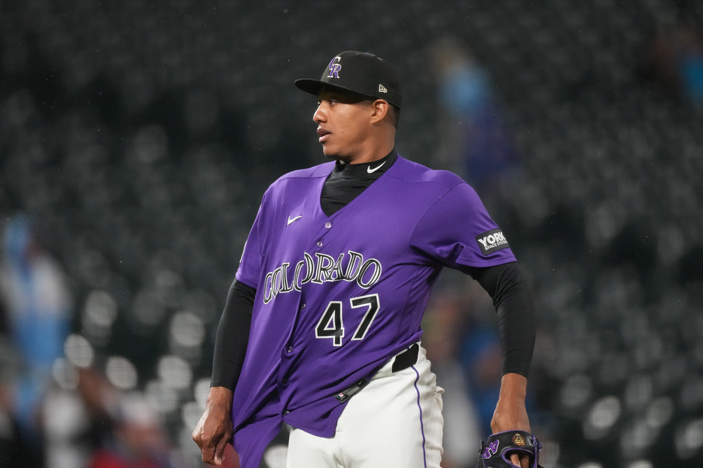 Colorado Rockies relief pitcher Juan Mejia pulls out his shirt after retiring Texas Rangers' Danny Jansen for the final out in a baseball game Monday, May 18, 2026, in Denver. (AP Photo/David Zalubowski)