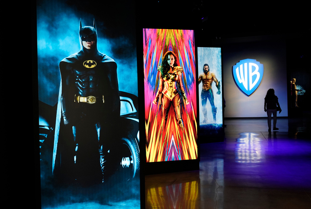 FILE - A visitor walks past portraits of DC Comics superheroes as she enters the "Action and Magic Made Here" interactive experience at the Warner Bros. Studio Tour Hollywood media preview on June 24, 2021, in Burbank, Calif. (AP Photo/Chris Pizzello, File)