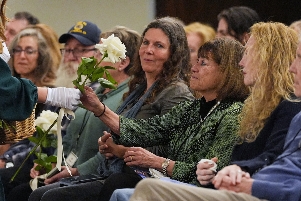 Roses are given to survivors on the one-year anniversary of the Palisades Fire in the Pacific Palisades neighborhood of Los Angeles Wednesday, Jan. 7, 2026. (AP Photo/Jae C. Hong)