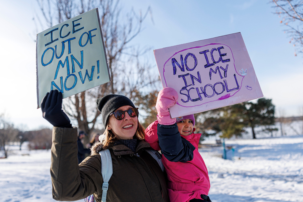 Demonstrator Bethany holds signs alongside her daughter Violet, 5, during a news conference at Lake Hiawatha Park in Minneapolis, on Friday, Jan. 9, 2026, demanding Immigration and Customs Enforcement be kept out of schools and Minnesota following the killing of 37-year-old mother Renee Good by federal agents earlier on Wednesday. (Kerem Yücel/Minnesota Public Radio via AP)