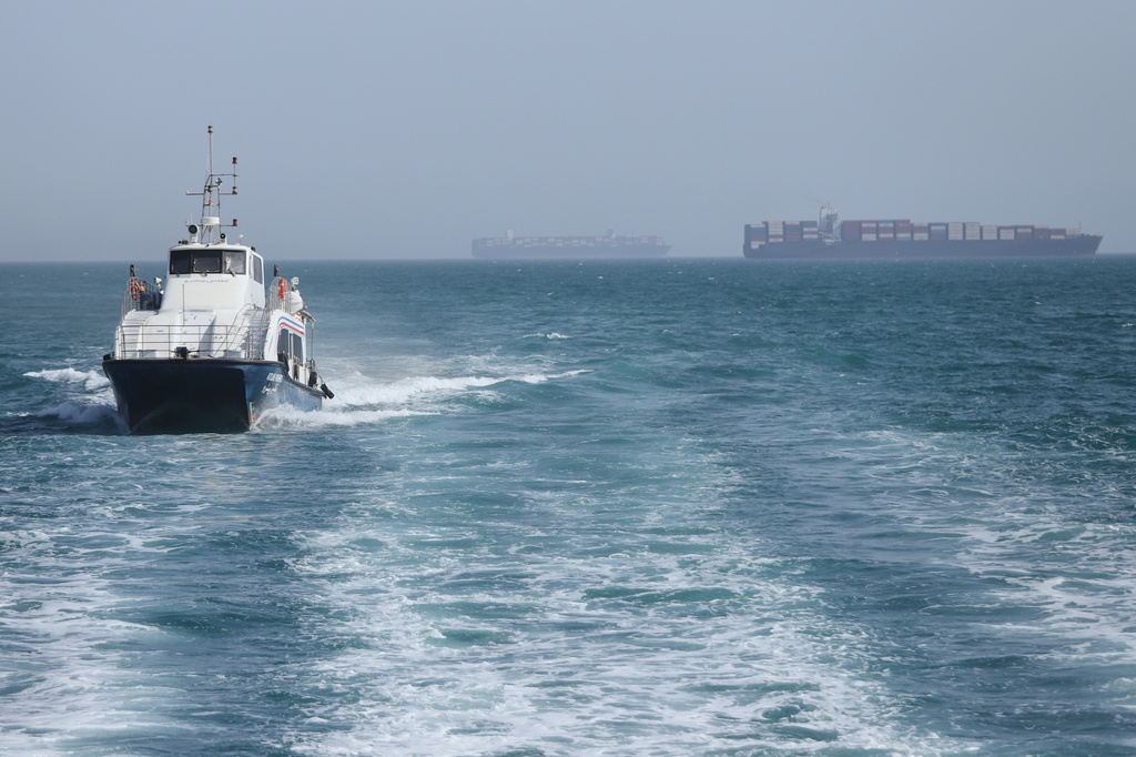 A patrol boat moves through the water as cargo ships sit at anchor in the Strait of Hormuz off Bandar Abbas, Iran, Saturday, May 2, 2026.(Amirhosein Khorgooi/ISNA via AP)