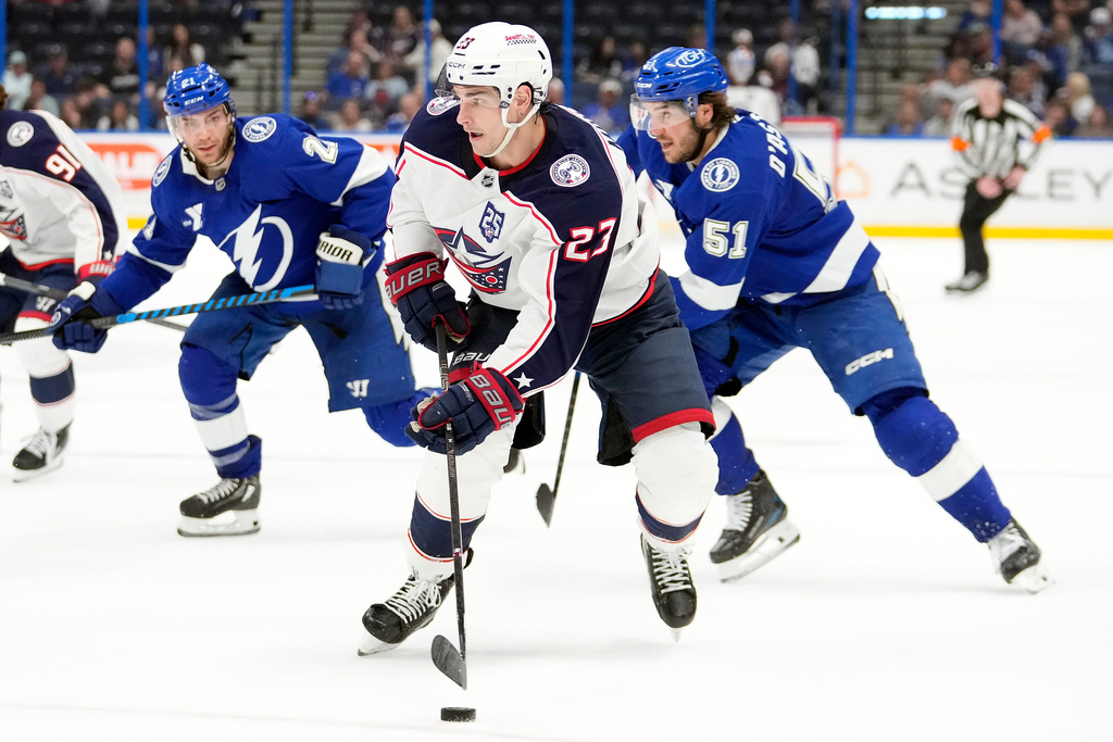 Columbus Blue Jackets center Sean Monahan (23) splits between Tampa Bay Lightning center Brayden Point (21) and defenseman Charle-Edouard D'Astous (51) during the third period of an NHL hockey game Tuesday, March 10, 2026, in Tampa, Fla. (AP Photo/Chris O'Meara)