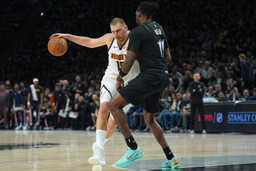 Denver Nuggets center Nikola Jokic, left, works toward the basket as Minnesota Timberwolves center Naz Reid (11) defends during the first half of Game 4 of a first-round NBA basketball playoff series, Saturday, April 25, 2026, in Minneapolis. (AP Photo/Abbie Parr)