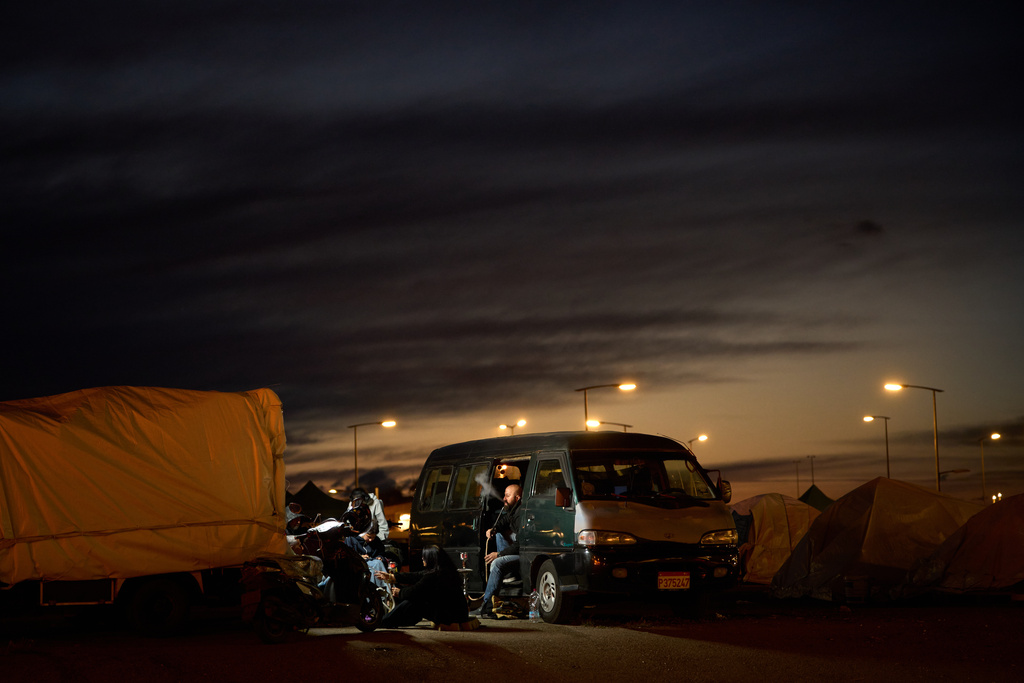 A man who fled Israeli strikes in southern Lebanon smokes in his van with his family outside a tent used as a shelter in Beirut, Lebanon, Wednesday, March 25, 2026. (AP Photo/Emilio Morenatti)