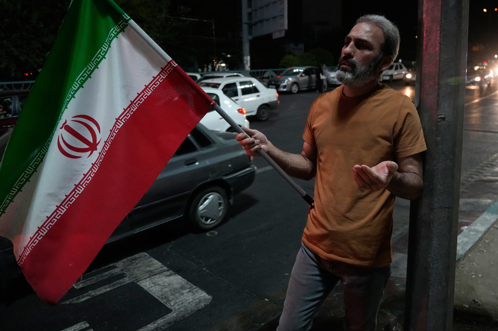 A demonstrator prays as he holds an Iranian flag in a pro-government gathering at a square in Tehran, Iran, Tuesday, July 28, 2026. (AP Photo/Vahid Salemi)