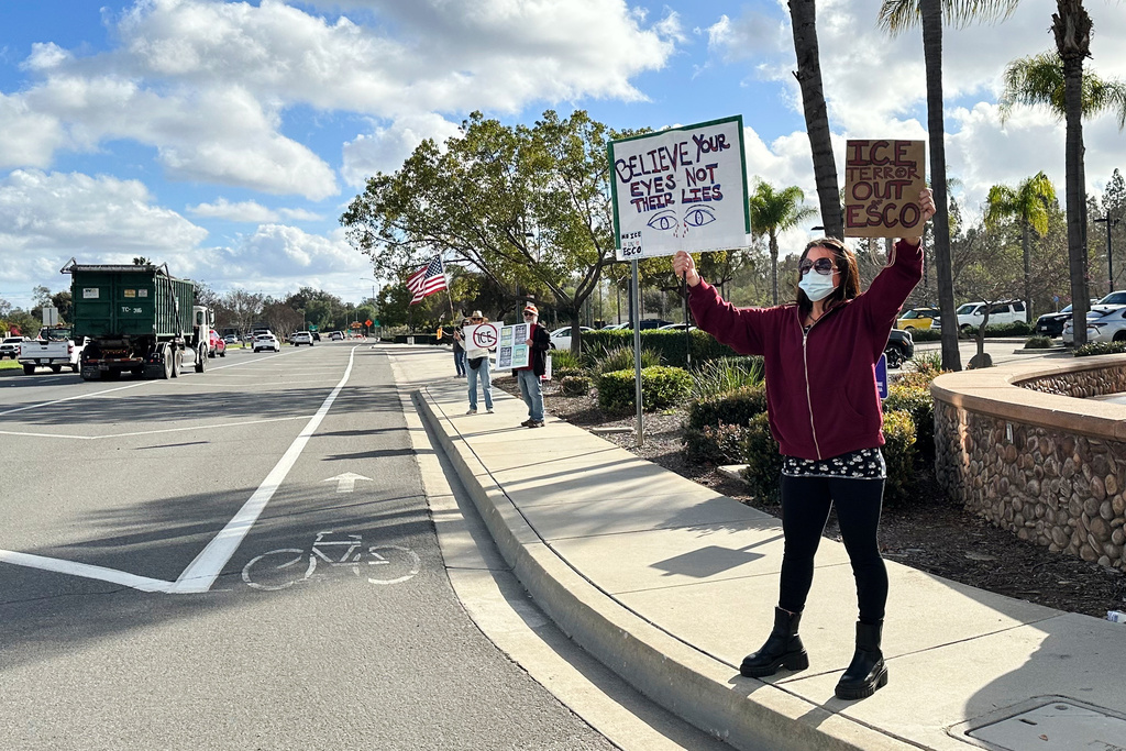 Demonstrators hold signs outside a police station on Wednesday, Feb. 18, 2026 in Escondido, Calif. (AP Photo/Amy Taxin)