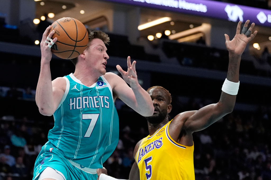 Charlotte Hornets guard Kon Knueppel passes around Los Angeles Lakers center Deandre Ayton during the first half of an NBA basketball game Monday, Nov. 10, 2025, in Charlotte, N.C. (AP Photo/Chris Carlson)