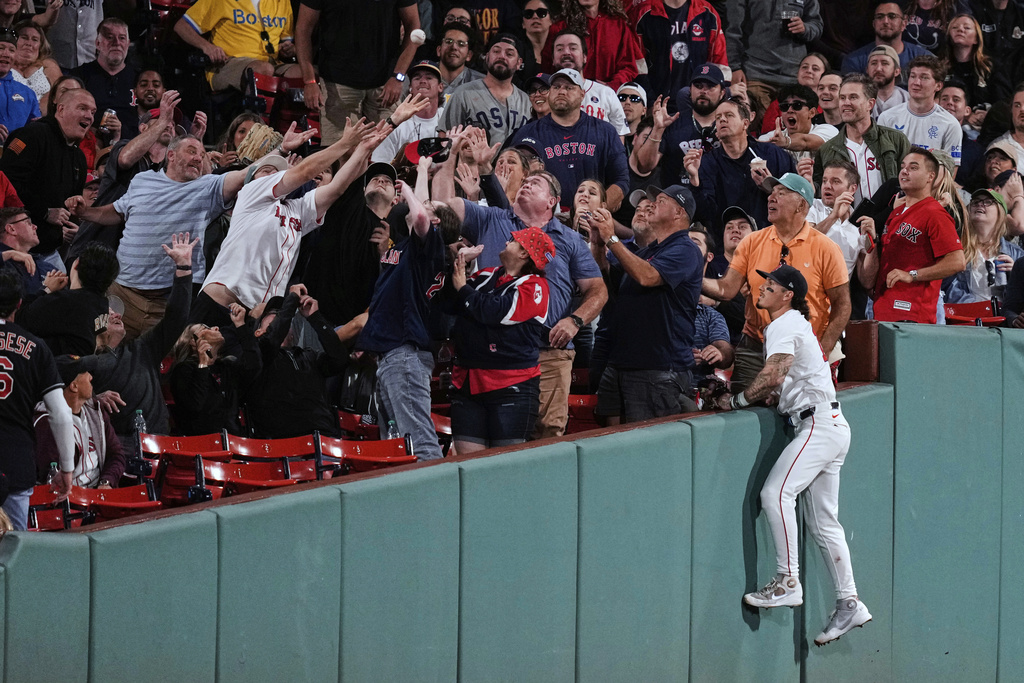 Boston Red Sox outfielder Jarren Duran, right, watches as fans try to make a catch on a foul ball by Cleveland Guardians' Steven Kwan during the fifth inning of a baseball game at Fenway Park, Wednesday, Sept. 3, 2025, in Boston. (AP Photo/Charles Krupa)