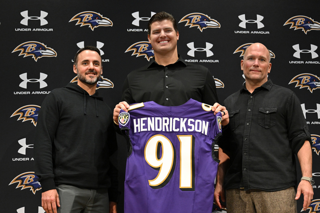 Baltimore Ravens, left to right, head coach Jesse Minter, defensive end Trey Hendrickson and general manager Eric DeCosta pose for a picture during an introductory NFL football press conference Friday, March 13, 2026, in Owings Mills, Md. (AP Photo/Gail Burton)
