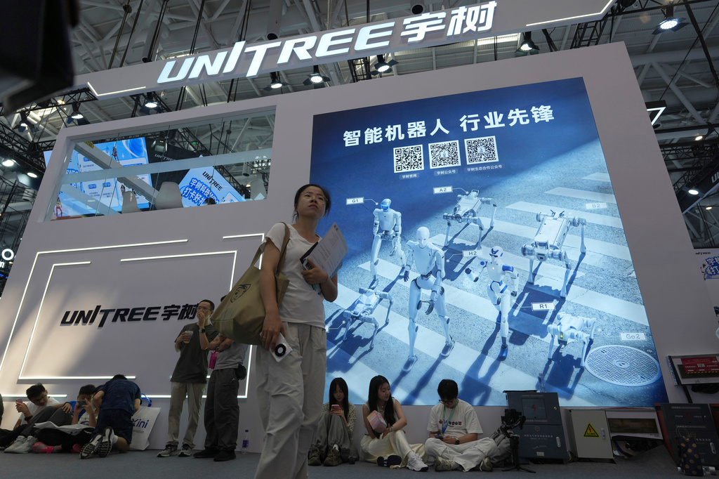 Attendees to the World Robot Conference hang out near the Unitree booth in Beijing, on Aug. 20, 2026. (AP Photo/Ng Han Guan)
