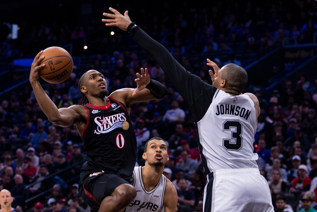 Philadelphia 76ers' Tyrese Maxey, left, goes up for the shot against San Antonio Spurs' Keldon Johnson, right, as Victor Wembanyama, center looks on during the second half of an NBA basketball game, Tuesday, March 3, 2026, in Philadelphia. (AP Photo/Chris Szagola)