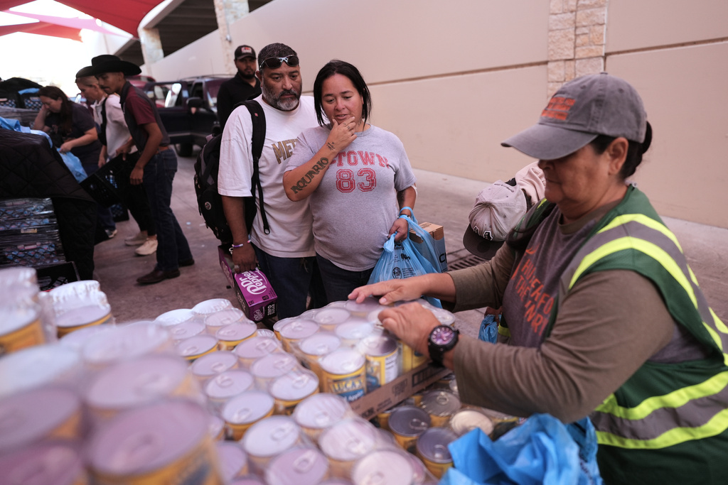 Volunteer Regie Robles, right, helps residents without a vehicle navigate a drive-through food distribution at the San Antonio Food Bank for SNAP recipients and other households affected by the federal shutdown, Thursday, Nov. 6, 2025, in San Antonio. (AP Photo/Eric Gay)