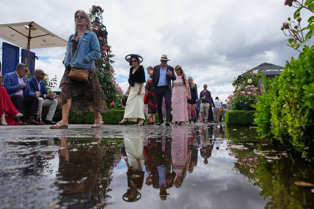 Spectators walk ahead of the Melbourne Cup horse race in Melbourne, Australia, Tuesday, Nov. 4, 2025. (AP Photo/Asanka Brendon Ratnayake)