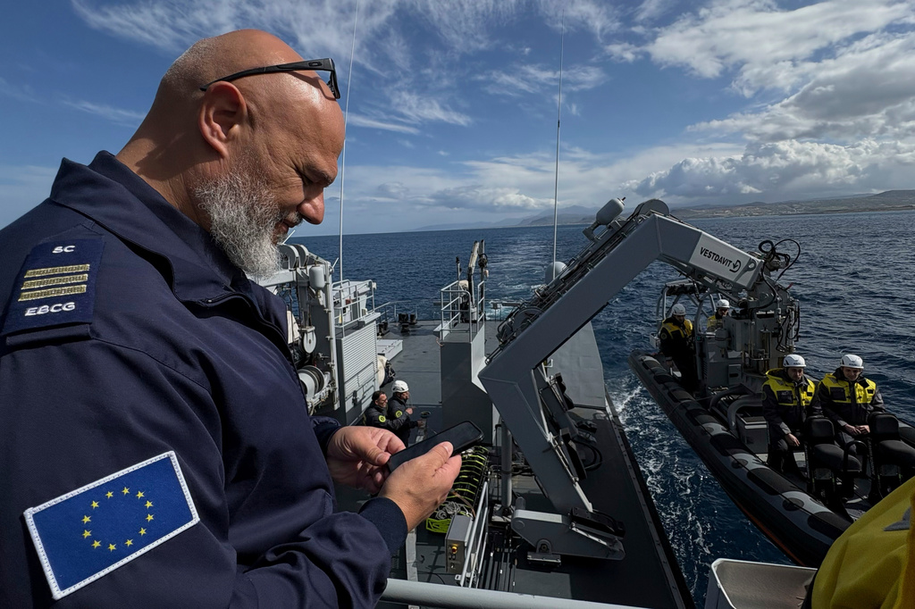 FILE - Frontex Contingent Commander Georgios Pyliaros takes pictures of Frontex officers from the Guardia di Finanza OPV Osum as they prepare in their speedboat to be lowered into the sea during a patrol in the Aegean Sea near Heraklion, Crete, Greece, Feb. 16, 2026. (AP Photo/Lefteris Pitarakis, File)