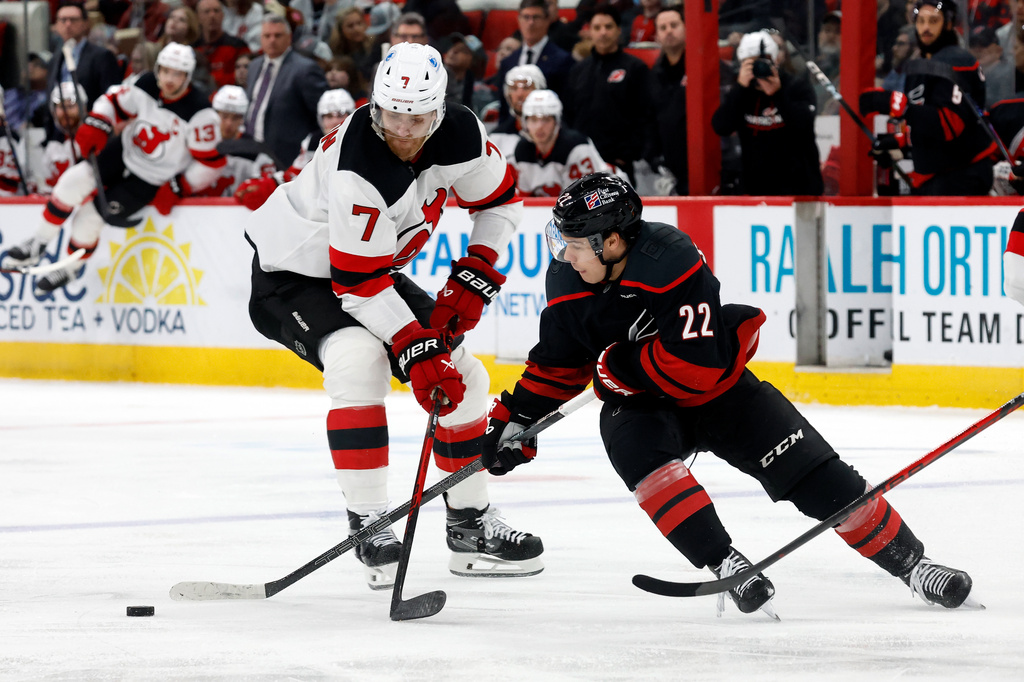 New Jersey Devils' Dougie Hamilton (7) takes the puck away from Carolina Hurricanes' Logan Stankoven (22) during the second period of an NHL hockey game in Raleigh, N.C., Saturday, March 28, 2026. (AP Photo/Karl DeBlaker)