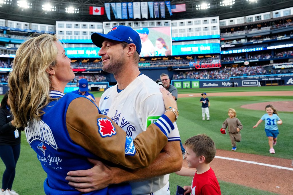 Toronto Blue Jays pitcher Max Scherzerfront right, hugs his wife Erica May-Scherzer, left, after playing the Cincinnati Reds in a baseball game in Toronto, Sunday, Sept. 27, 2026. (Frank Gunn/The Canadian Press via AP)