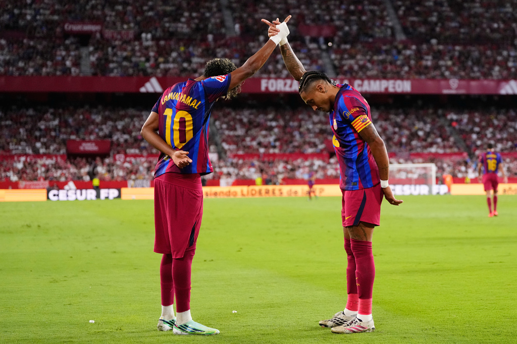 Barcelona's Raphinha, right, celebrates with Lamine Yamal after scoring his side's second goal the Spanish La Liga soccer match between Sevilla and Barcelona in Seville, Spain, Saturday, Sept. 19, 2026. (AP Photo/Jose Breton)